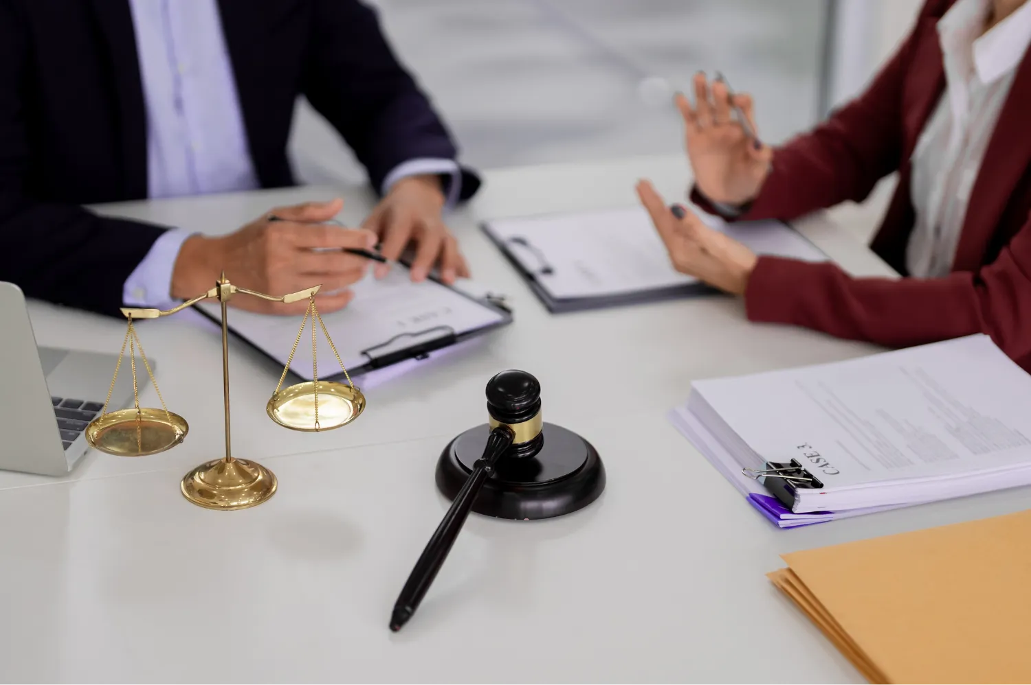 Lawyers discussing legal case documents beside scales of justice and judge gavel